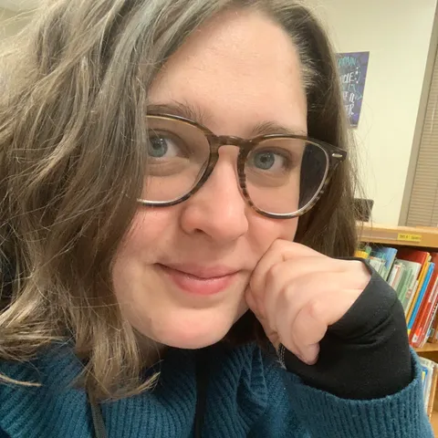 Katelyn Combs smiling in front of a bookshelf