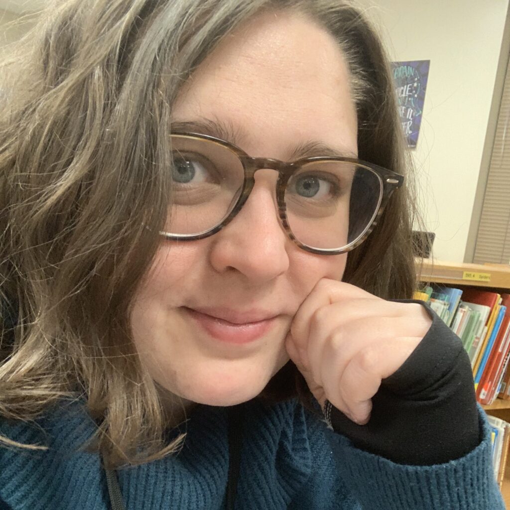 Katelyn Combs smiling in front of a bookshelf